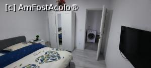 P19 [MAR-2025] Bârlad, Apartament Elena, Dormitorul cu pat, șifonier și televizor; se vede holul cu mașina de spălat